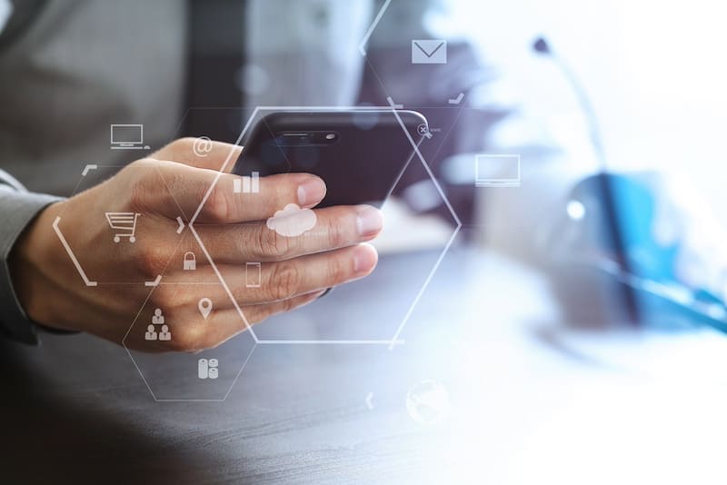 Hands holding smartphone with digital overlay showing business communication icons in hexagonal patterns